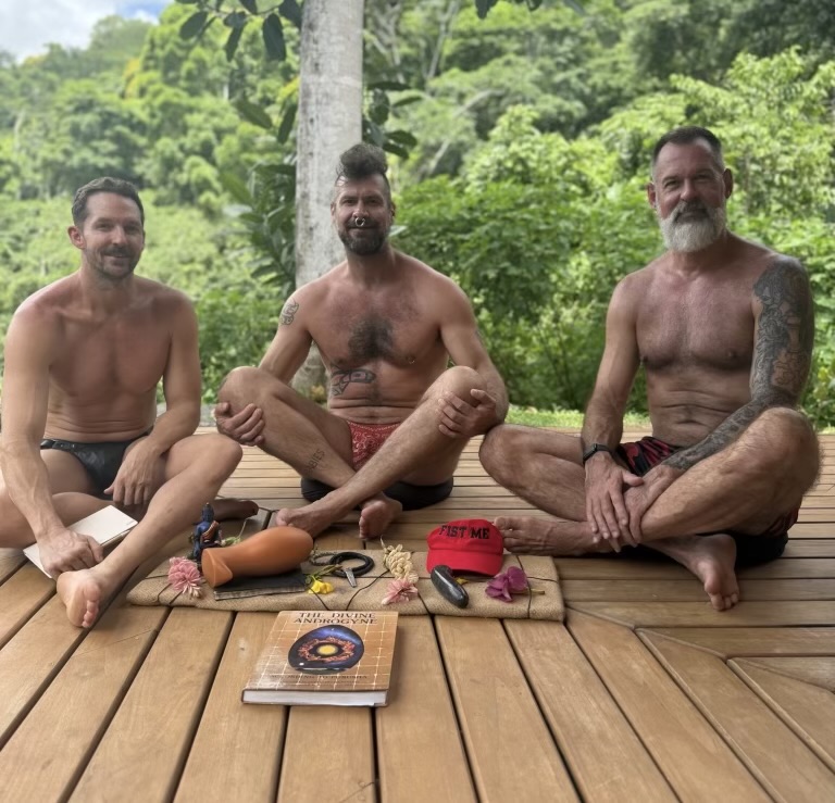 Alex, Shelby and Hunter seated together on a wooden deck around The Divine Androgyne at Qasa Retreat Center in Costa Rica