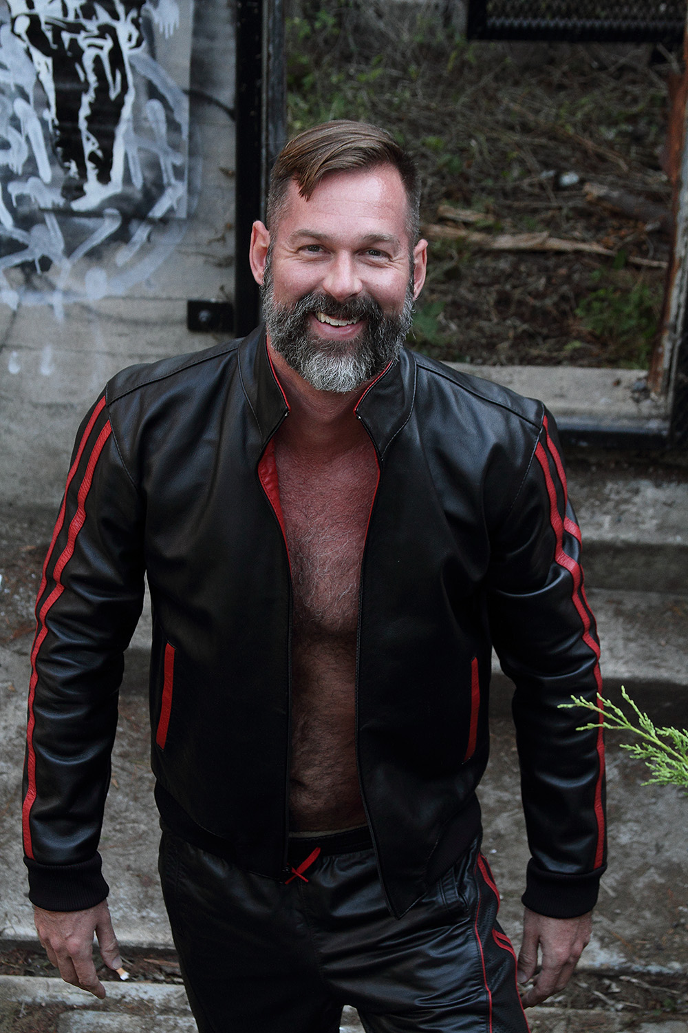 Alex laughing in a black and red leather jacket